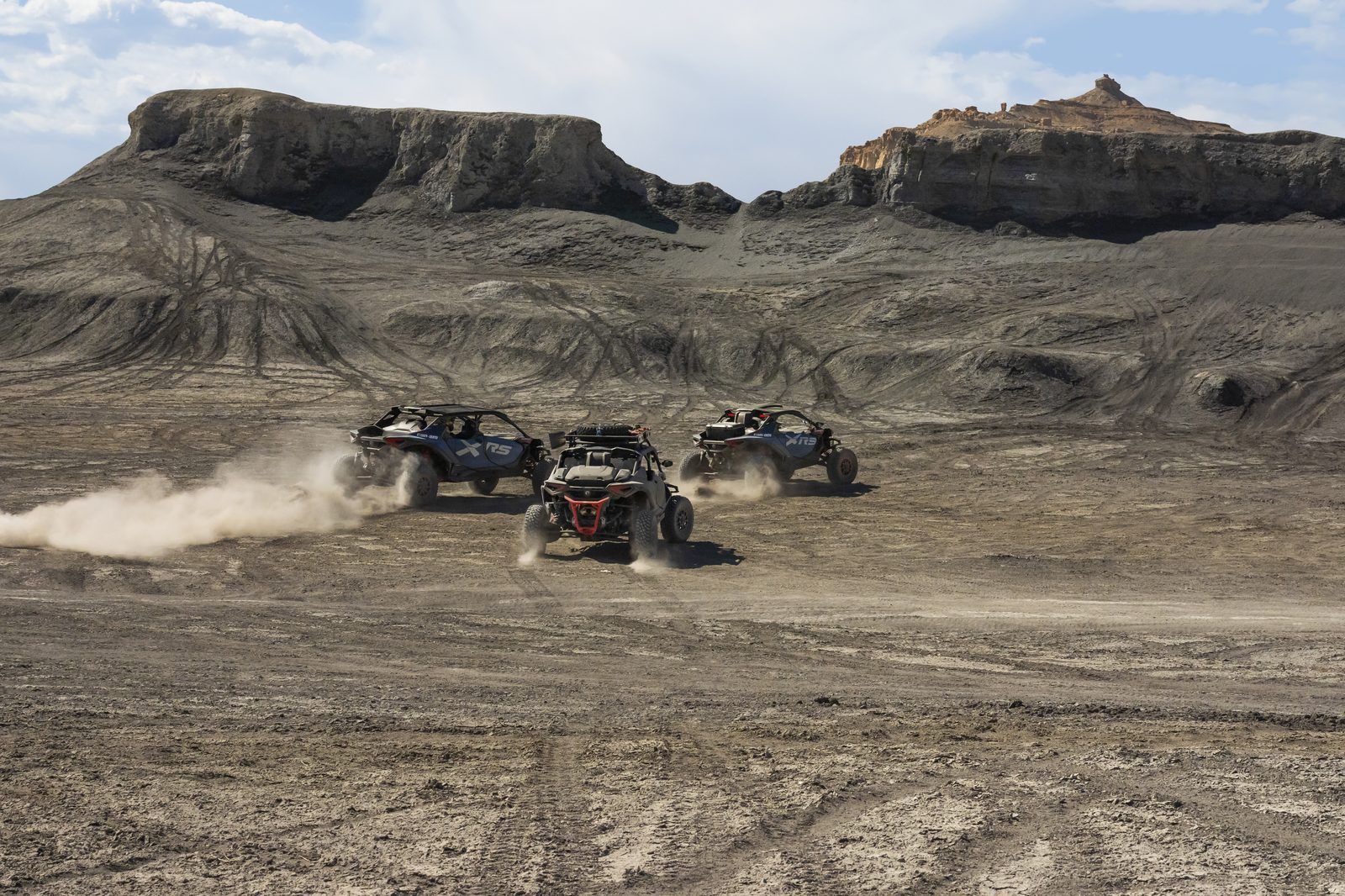 Can-Am UTVs kicking up dust in wide desert terrain