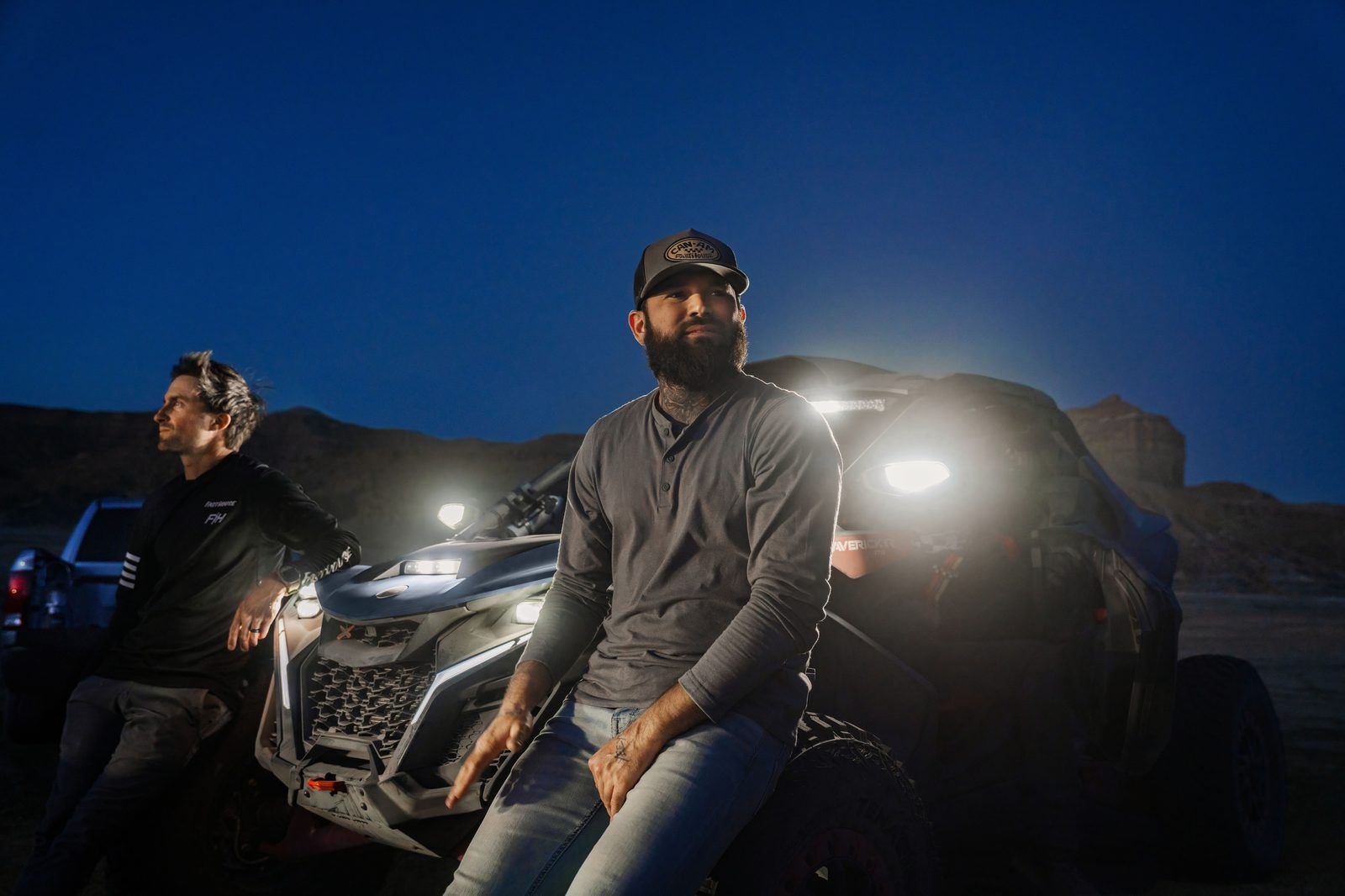 Riders resting beside a Can-Am UTV at dusk
