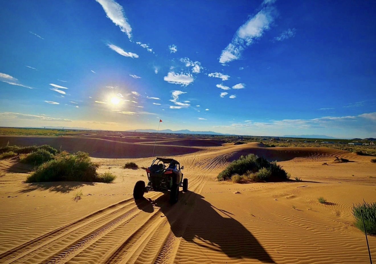 A Can-Am UTV parked on the Red Sands dunes at sunset